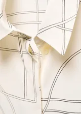 Camisa de tejido fluido con diseño recto, cuello camisero, y manga larga abotonada, con cierre de botones en la parte delantera.