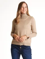 Polera tejida en hilado fino color beige, con cuello alto y manga larga con tajo en el puño.