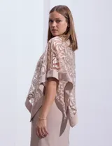 Vestido de fiesta color beige, de corte recto y largo a la rodilla, confeccionado en seda fría. Presenta una sobrecapa de microtul bordado con motivos florales.