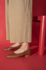 Zapato chata color dorado, trenzado a mano en cuero vacuno, con capellada, forro y plantilla de cuero vacuno.