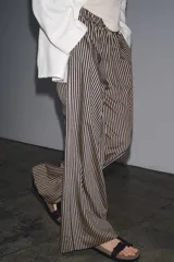 Pantalón de tiro medio con cintura elástica y bolsillos laterales ocultos en costura. Pierna ancha y diseño a rayas verticales azules y blancas.