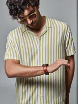 Camisa de manga corta con rayas verticales verdes y blancas, cuello clásico y cierre con botones.