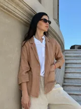 Blazer color marrón claro, de lino, con solapas de muesca, cierre de un botón, mangas 3/4 y bolsillos de parche.