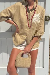 Camisa blanca de lino con bordado de una palmera en el pecho.