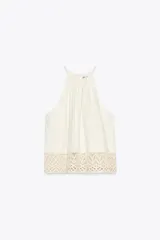 Top blanco de cuello halter con detalle de crochet en el ruedo.