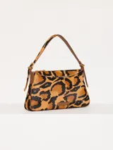 Cartera tipo baguette con estampado animal print de leopardo, confeccionada en cuero con pelo y detalles en cuero vacuno flor. Tiene correa regulable en combinación de cuero y pelo, con hebillas metálicas personalizadas.