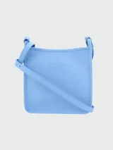 Bandolera Longchamp modelo Le Foulonné, color crudo, con correa fina regulable, cierre superior y logo grabado en el frente.