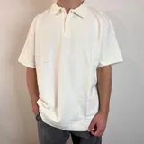 Chomba color crema con cuello polo, corte oversize y tejido acanalado vertical.