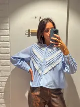 Camisa blanca de mangas largas con cuello alto y detalles de encaje.