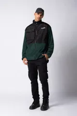 Campera negra con la parte superior de tela tipo rompevientos con dos bolsillos con solapa y la parte inferior de micro polar. Tiene cierre frontal y cuello alto.