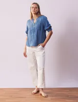 Blusa de lyocell color celeste, con cuello a la base, escote en V y botones. Delantera con bolsillo. Manga corta con terminación en punto smock.