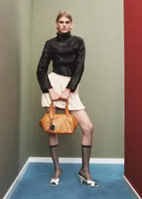 Chaqueta negra de cuero ovino con cuello alto abotonado, corte recto y bolsillos de solapa con botón en el frente.