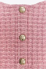Top corto rosado de tejido tweed con tirantes finos y escote recto. Cierre frontal con tres botones metálicos dorados en relieve.