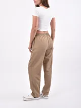 Pantalón de vestir color negro, de corte recto, con bolsillos laterales y traseros. Se ajusta a la cintura con cinturón de cuero marrón.