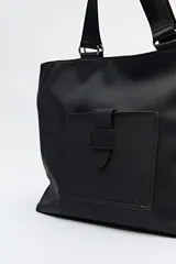 Bolso blanco de símil cuero con terminación suave. Tiene asas anchas de cinta negra y un bolsillo frontal con solapa.