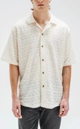 Camisa de manga corta color crema con calados en forma de rombos.