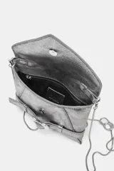 Bolso formato bandolera color plateado metalizado, con solapa frontal que simula un cinturón con hebilla metálica en forma de corazón. Posee asa fina de cadena y cierre mediante botón imantado.