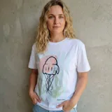 Remera blanca de manga corta con cuello redondo y un estampado central de una medusa en tonos rosados y verdes pastel.