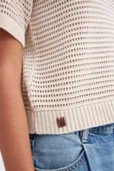 Remera color crudo de tejido calado con cuello polo y mangas cortas.