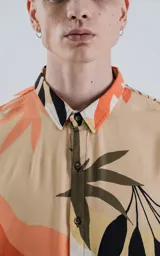Camisa de manga larga con estampado de hojas en tonos beige, naranja, negro y verde.