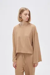 Top color beige de manga larga, holgado y cuello redondo.