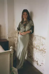 Vestido midi color verde oliva de tejido satinado, con cuello barco, mangas cortas abullonadas con puños y aplicación de encaje a contraste en la parte superior. Cierre trasero con cremallera oculta y botones forrados.