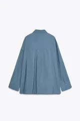 Camisa rosa claro confeccionada en hilatura con modal, de corte holgado, con cuello solapa, manga larga terminada en puño, dos bolsillos con solapa en el delantero y cierre frontal con botones.