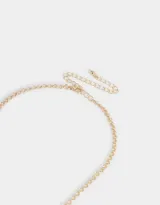 Collar corto dorado con cadena de eslabones y dijes colgantes: dados, cerezas, naipe y serpiente.
