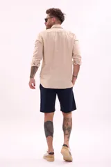 Camisa de manga larga color beige claro, de corte clásico y confeccionada en tejido texturizado.