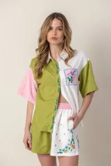 Camisa de mangas cortas con diseño color block en verde, blanco y rosa. Tiene un bolsillo con bordado de ave y flores bordadas en el frente.