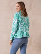 Campera blanca con bordado floral en verde agua, cuello solapa, cierre con botones, bolsillos delanteros y ruedo fruncido.