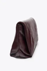 Bolso bandolera tipo sobre color borgoña, con asa fina y cierre imantado con solapa. Incluye bolsillo interior con cierre de cremallera metálica.