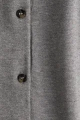 Cárdigan gris de punto fino con cuello redondo, manga corta y cierre frontal con botones. Tiene terminaciones acanaladas en cuello, puños y ruedo.