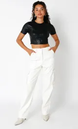 Crop top negro de cuero sintético, elastizado y forrado, con busto marcado estilo corset y mangas cortas.