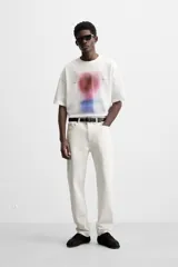 Camiseta blanca de corte relaxed fit, cuello redondo y manga corta. Estampado combinado a contraste en el delantero con imagen borrosa de flor y texto en azul.