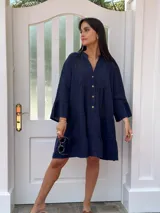 Vestido corto azul marino de lino, con cuello mao, mangas 3/4 acampanadas y cierre frontal con botones de coco. Diseño amplio con corte escalonado.