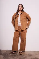 Sobrecamisa negra de gamuza vegana con calce oversize, cuello camisero, cierre con botones a presión, mangas largas con puños abotonados y bolsillos de parche en el pecho.