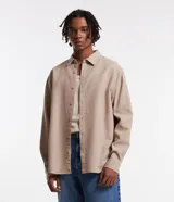 Camisa beige de tricolina texturizada, corte amplio, manga larga y abotonada al frente.