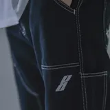 Pantalón negro de gabardina, corte recto, con costuras blancas contrastantes y bolsillos laterales.