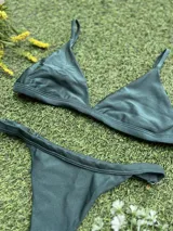 Conjunto de bikini verde oscuro, con corpiño triangular fijo y bombacha colaless regulable. Incluye abertura para agregar tazas soft.