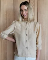 Camisa color beige claro con cuello con volados y mangas 3/4 abullonadas.