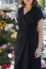 Vestido negro de lino con cuello y manga corta, corte a la cintura con lazo ajustable.