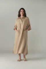 Vestido largo color beige de lino, con cuello camisero, media cartera con un botón, mangas 3/4 con tajos y bolsillos laterales.