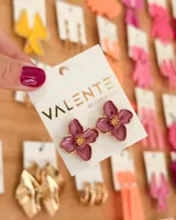 Par de caravanas con forma de flor color borgoña con centro dorado.