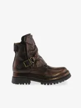 Botín de cuero bovino color bronce metalizado, estilo motociclista, con caña arrugada y hebilla decorativa. Presenta suela de plataforma gruesa con dibujo de neumático.