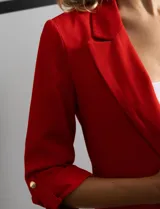 Blazer rojo de crepe marca Tahari, con cuello con solapa y abertura central. Tiene mangas 3/4 regulables con presilla y botón, bolsillos delanteros y forro interno.