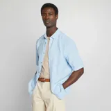 Camisa celeste de lino con corte regular, cuello clásico y manga corta.