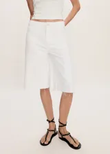 Short blanco de tiro bajo, corte holgado y largo a la rodilla, con cierre de cremallera y botón, trabillas, dos bolsillos delanteros de parche, bolsillo monedero, bajo deshilachado y dos bolsillos traseros de parche.