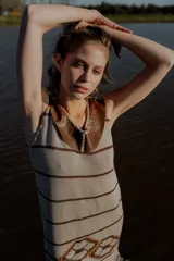 Vestido corto tejido en hilado de algodón color beige con rayas horizontales marrones, cuello de cuero marrón y terminación con flecos. Presenta un diseño geométrico en la parte inferior.