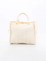 Bolso tipo tote bag color crudo, de tela rígida con doble asa corta y bolsillos laterales.